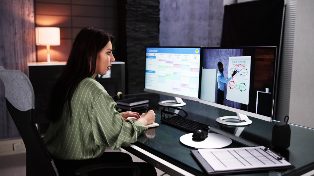 Chica frente a dos monitores de ordenador asistiendo a una formación online